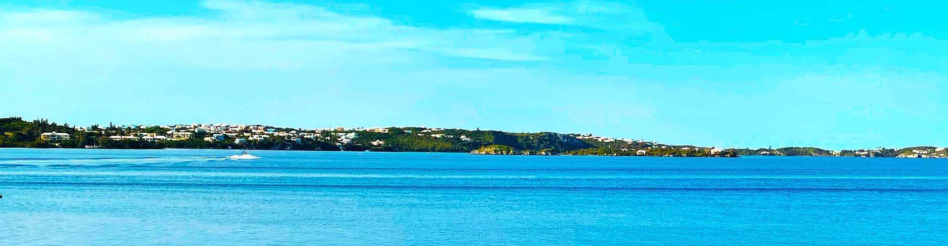Bermuda coastline with homes along the hillside across calm blue water